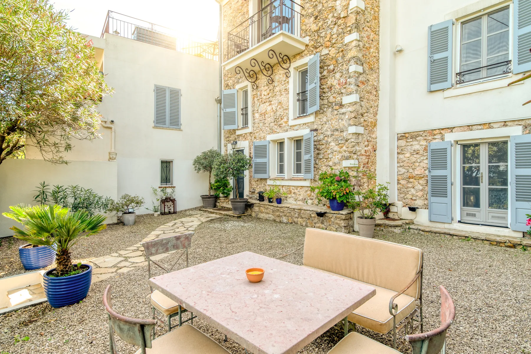 The Provençal stone courtyard and pale blue shutters at Mas Fleuri